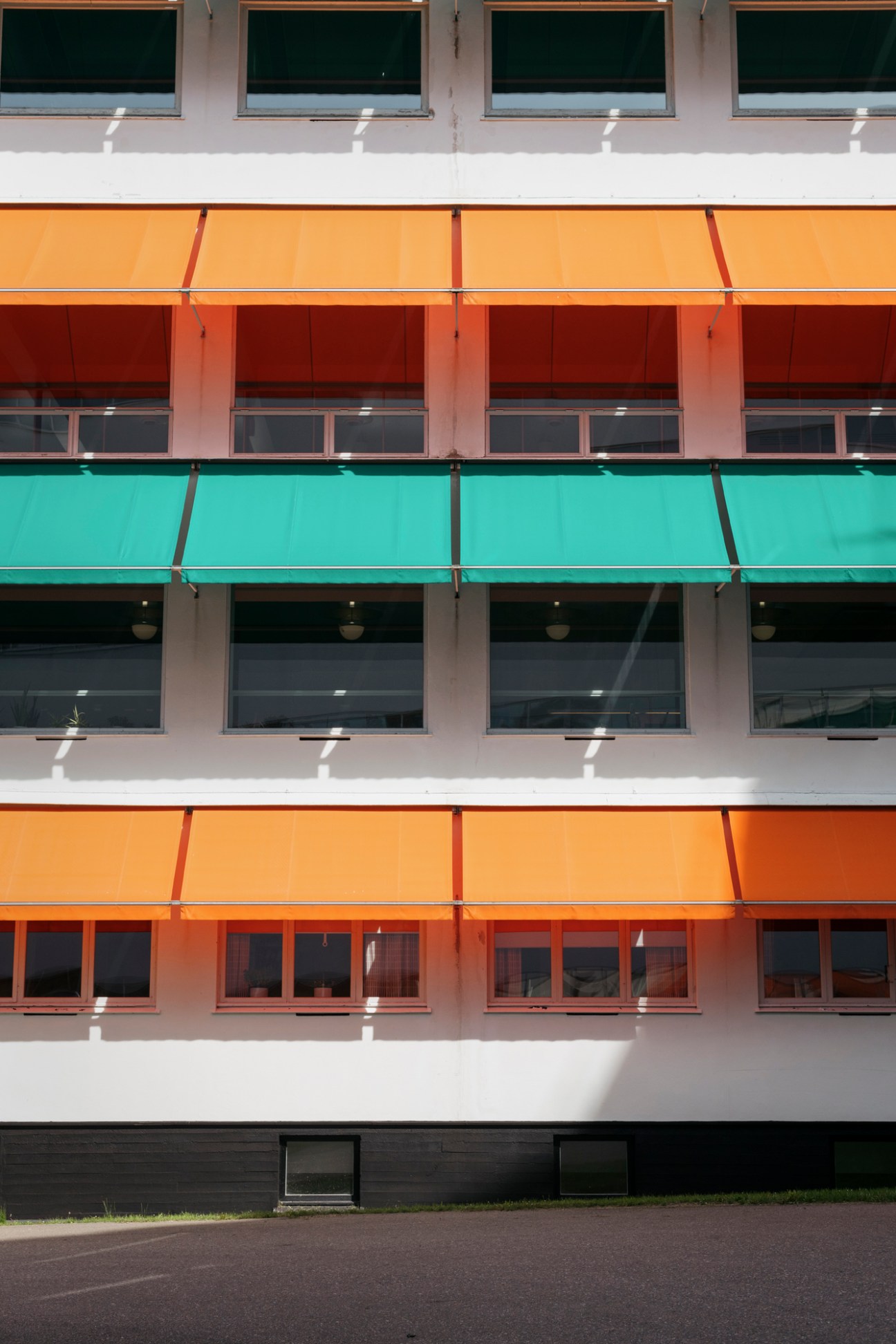 Colorful awnings on the B-wing façade of Paimio Sanatorium featuring yellow, red, and turquoise horizontal bands.