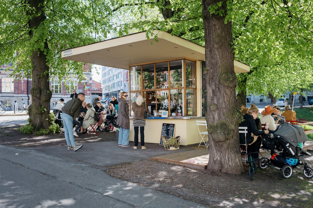 Customers queue at Kiosque, a Helsinki kiosk serving French café classics, with staff taking orders through the window.