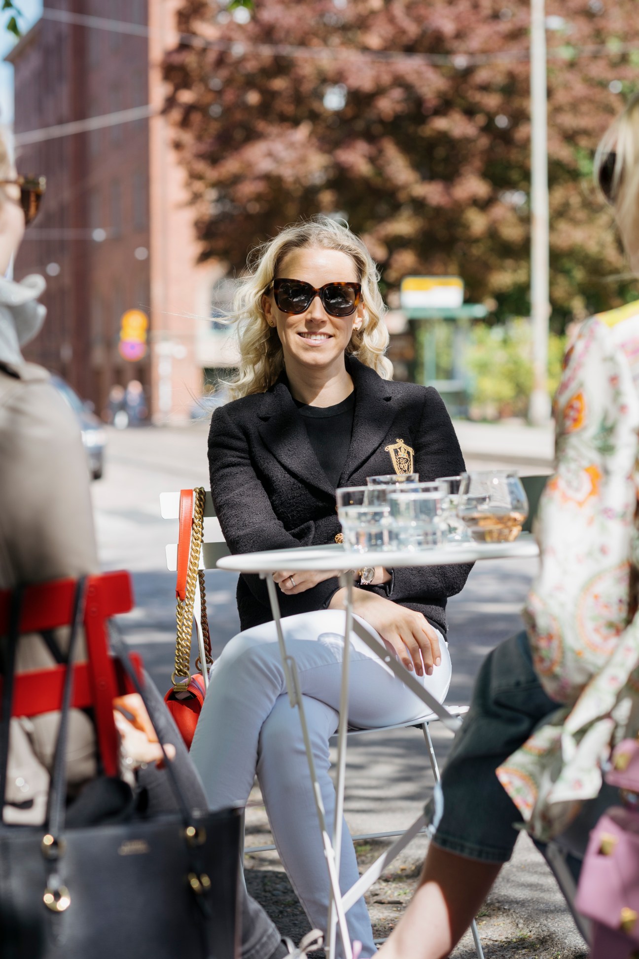 Woman in black blazer and sunglasses serving drinks at an outdoor kiosk in Helsinki.