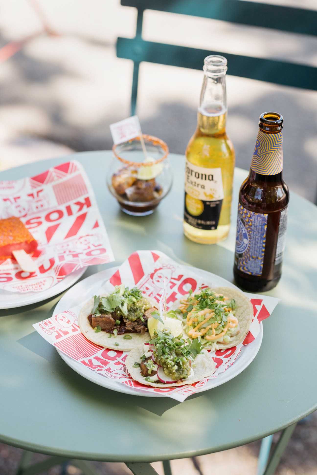 Plate of tacos with Corona and craft beer on outdoor table at Helsinki kiosk.