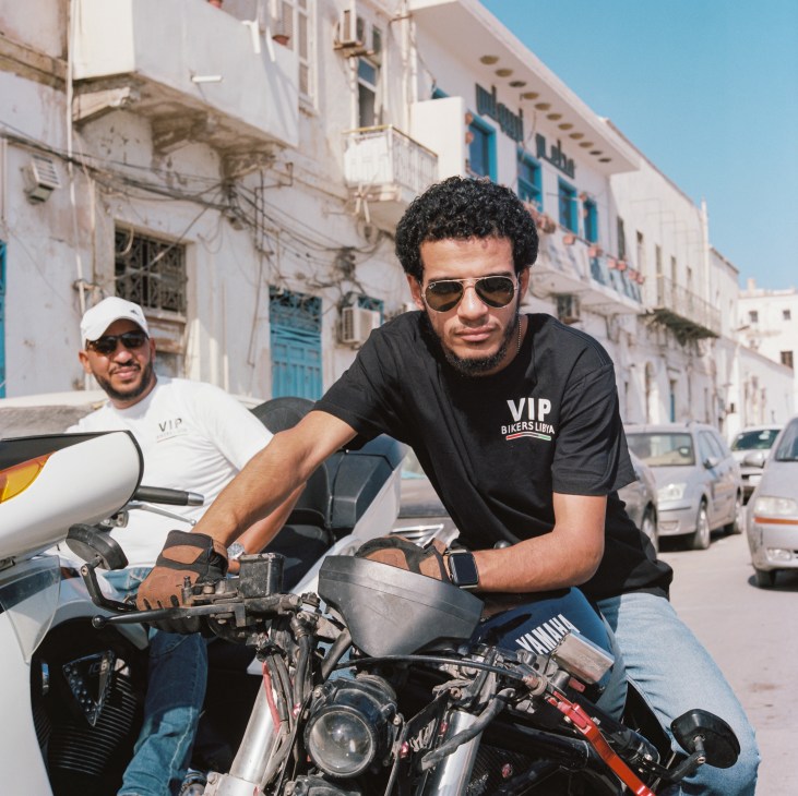 Hamza al Fakeh of Tripoli's VIP Bikers Club sitting on motorcycle in white Mediterranean street setting