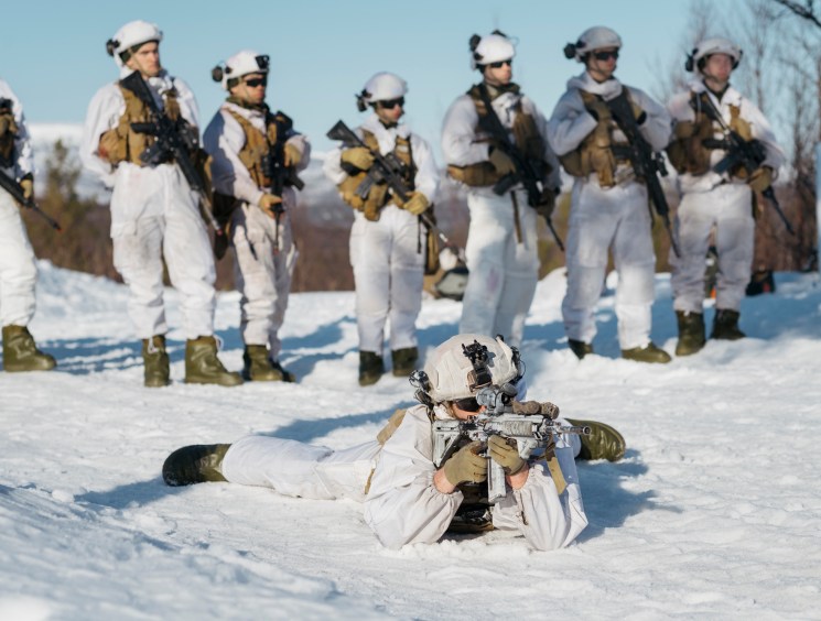 Norwegian conscripts in white winter camouflage uniforms training in snow during Cold Response NATO exercise.