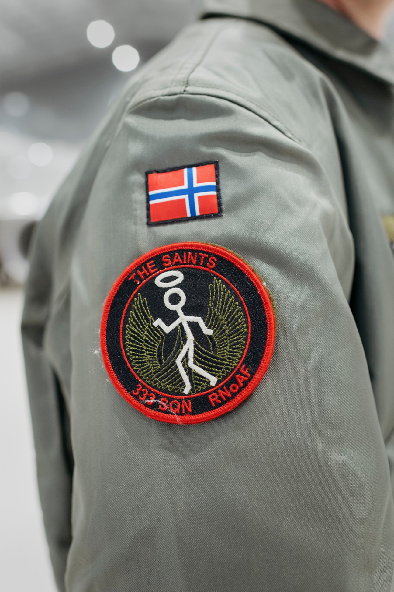 Close-up of Norwegian Air Force 333 Squadron insignia patch on grey flight suit with Norwegian flag above it.