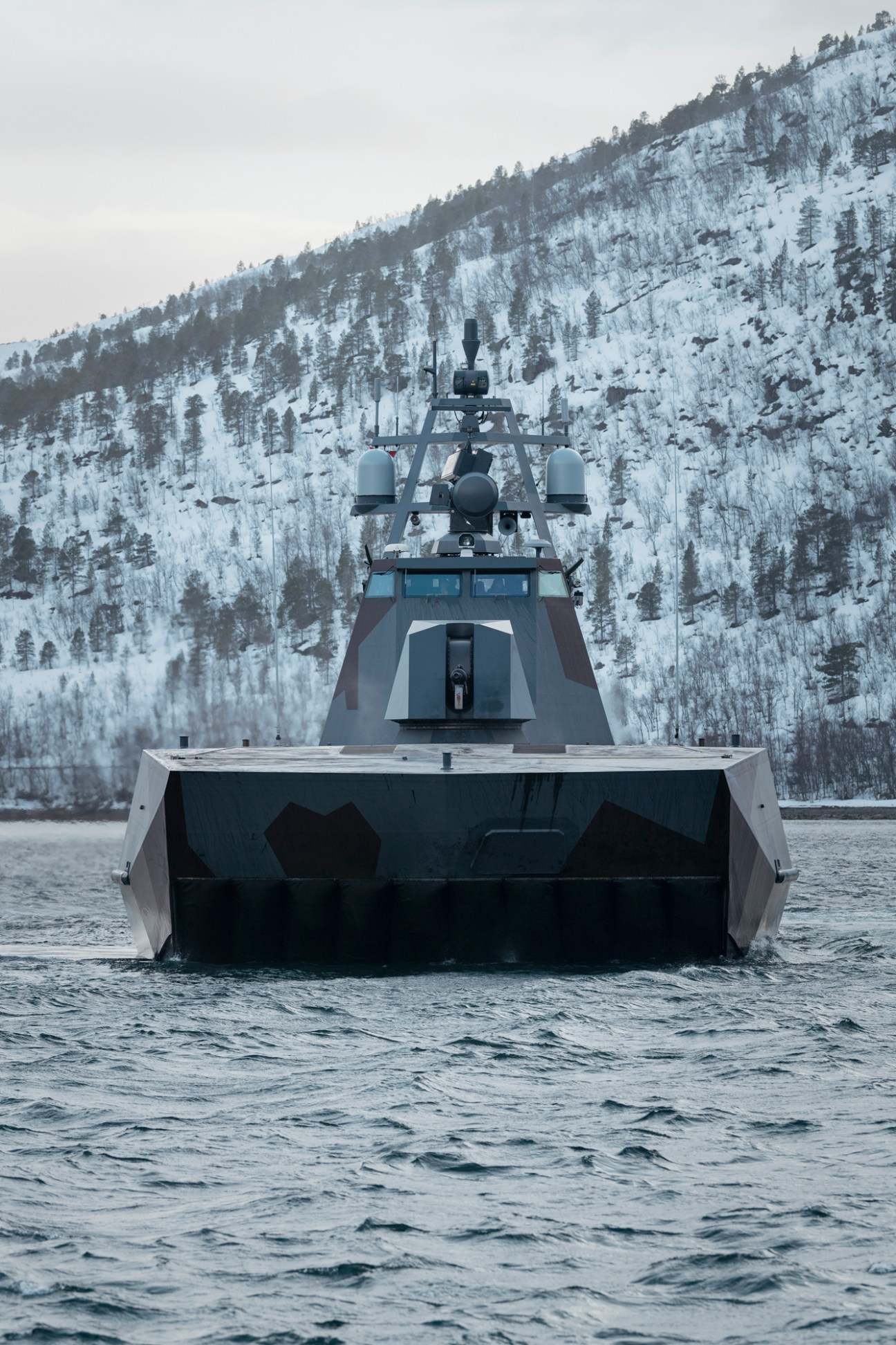 KNM HNoMS Steil stealth corvette in Arctic waters with snow-covered mountains in background