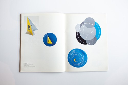 Open magazine spread showing geometric circular and triangular design elements in blue and yellow on white pages.