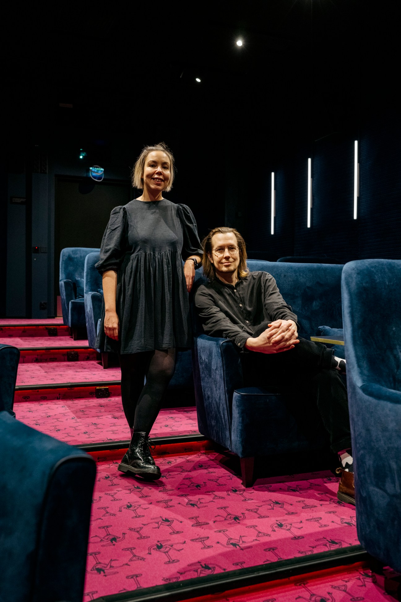 Hanna Hynynen and Atte Laurila standing in cinema with blue velvet seats and red patterned carpet