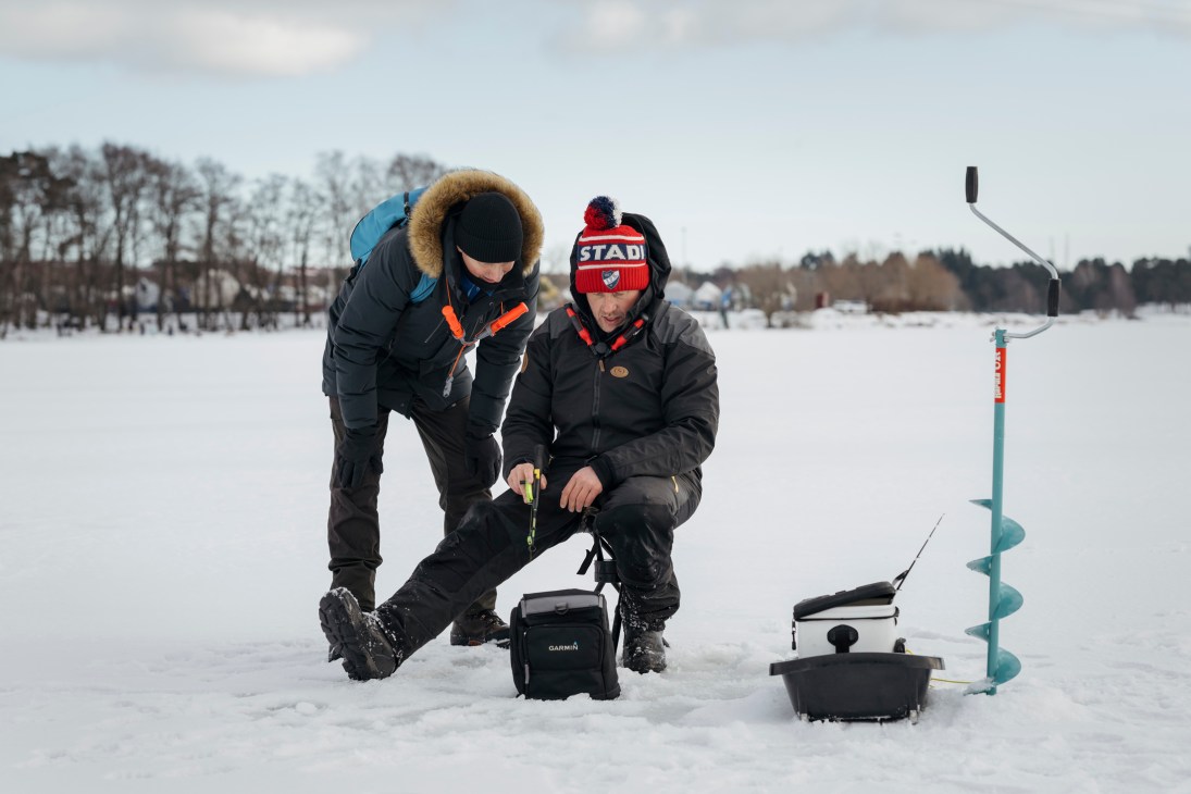 Ice fishing instructor demonstrating equipment on frozen Helsinki bay