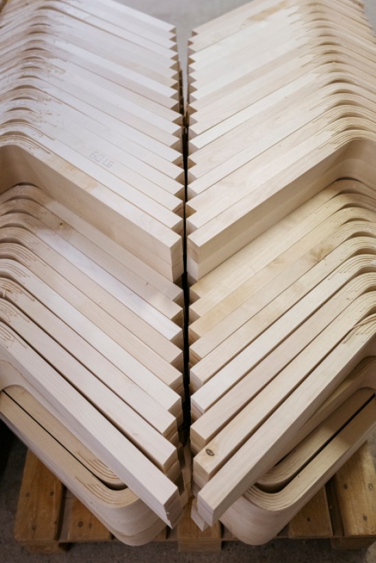 Workers in a factory assembling wooden L-legs for Artek furniture, showing the precise craftsmanship involved in the production process