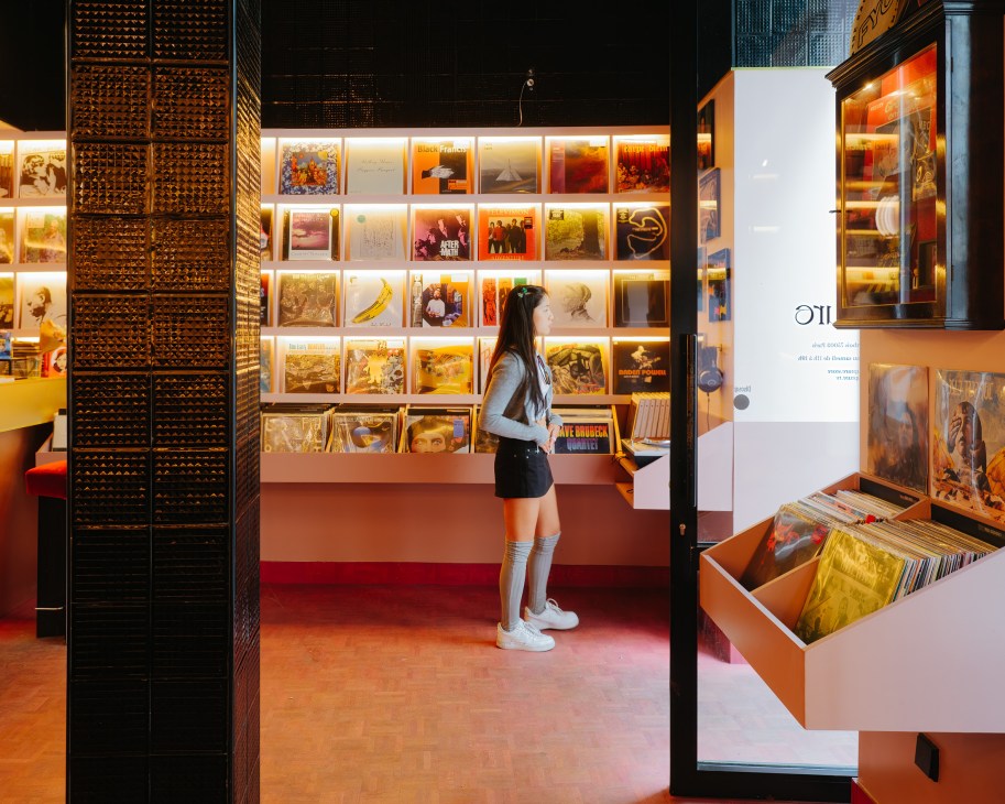 Woman browsing vinyl records at Rupture Records Paris with illuminated record display wall