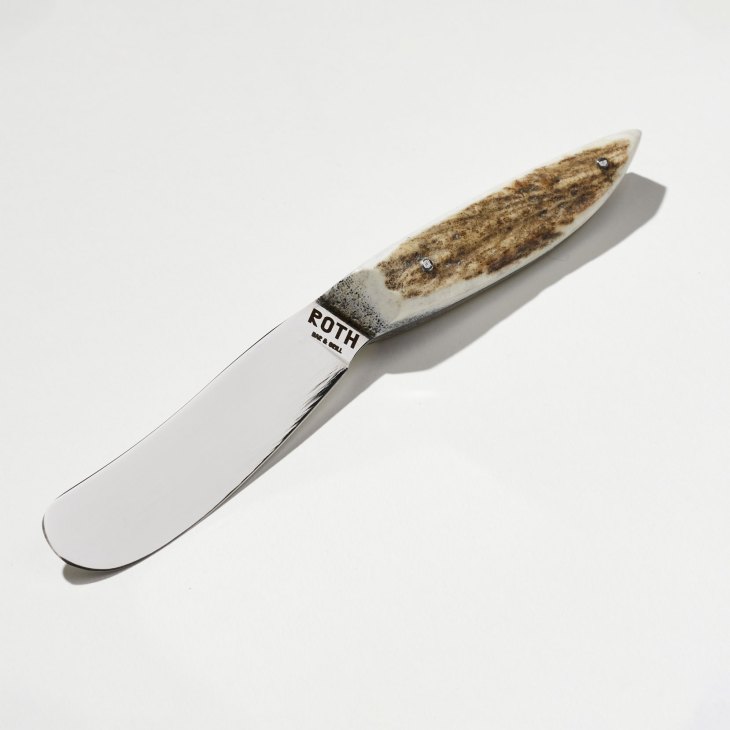 Laguiole butter knife with textured wooden handle and stainless steel blade on white background.
