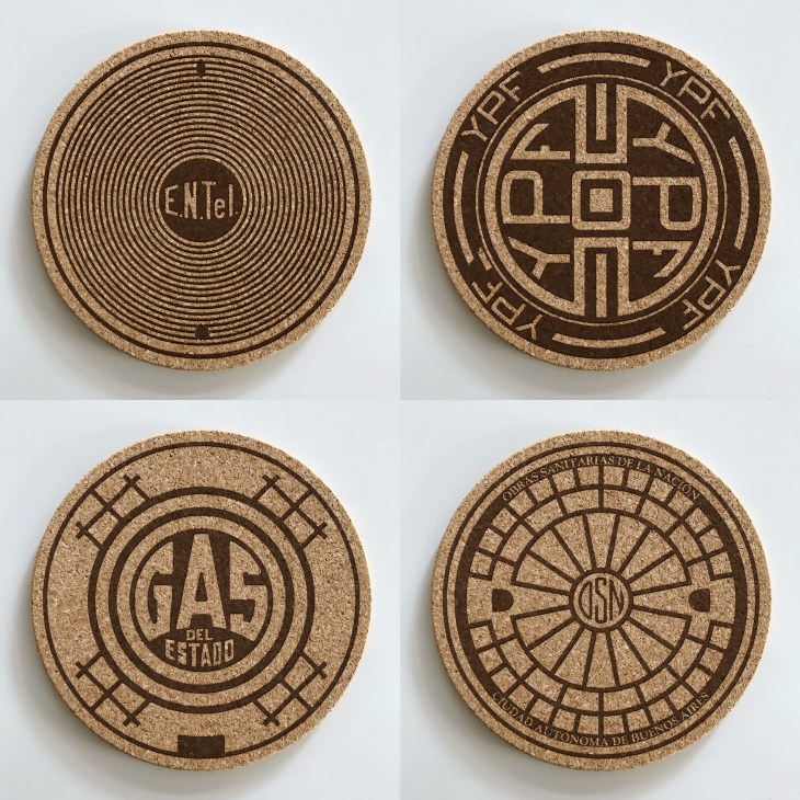 Four decorative cork coasters featuring different manhole cover designs from cities around the world