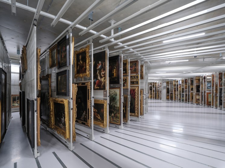 Interior storage facility with paintings in ornate frames mounted on moveable metal storage racks