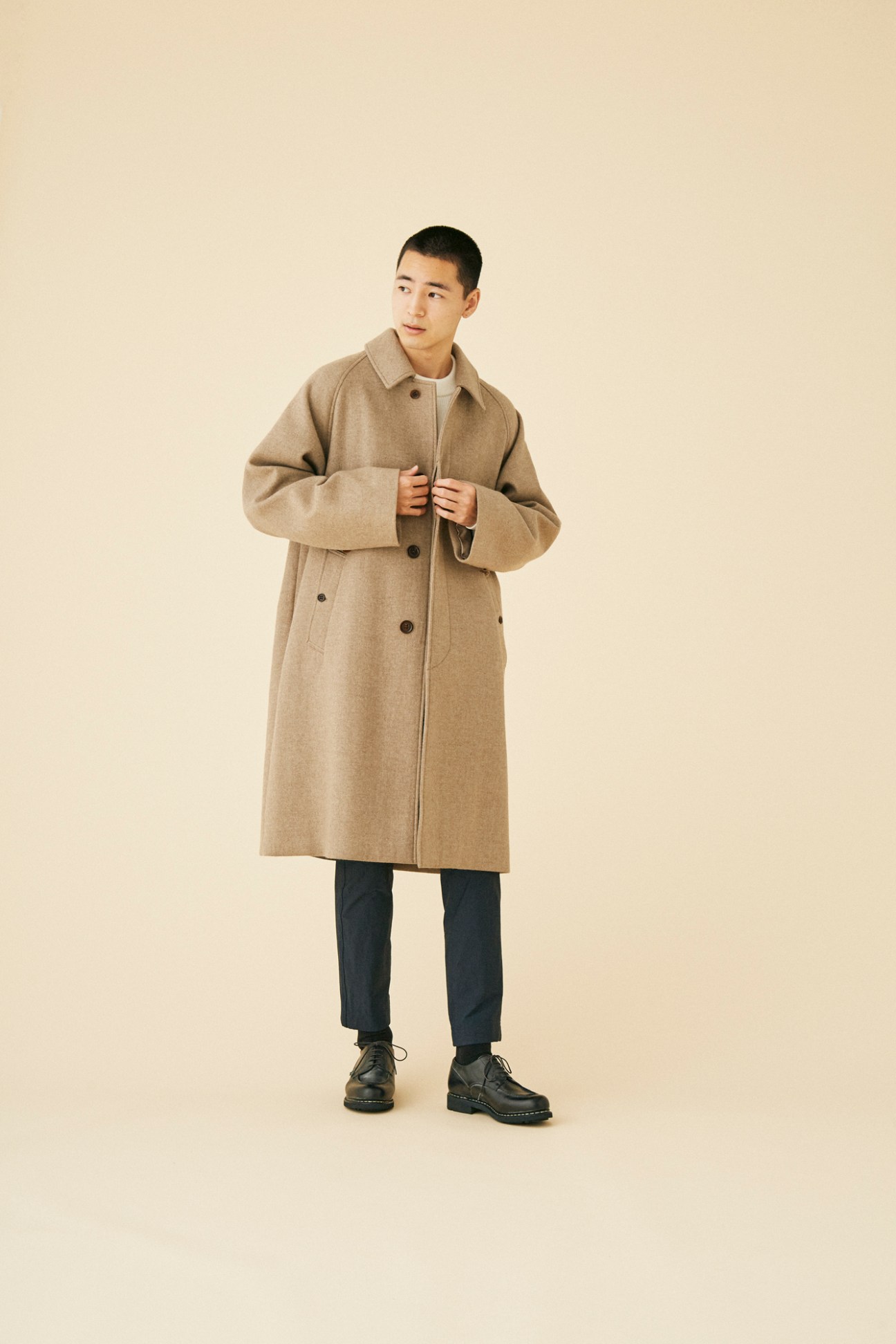 Man wearing relaxed beige wool coat by Herill against neutral background
