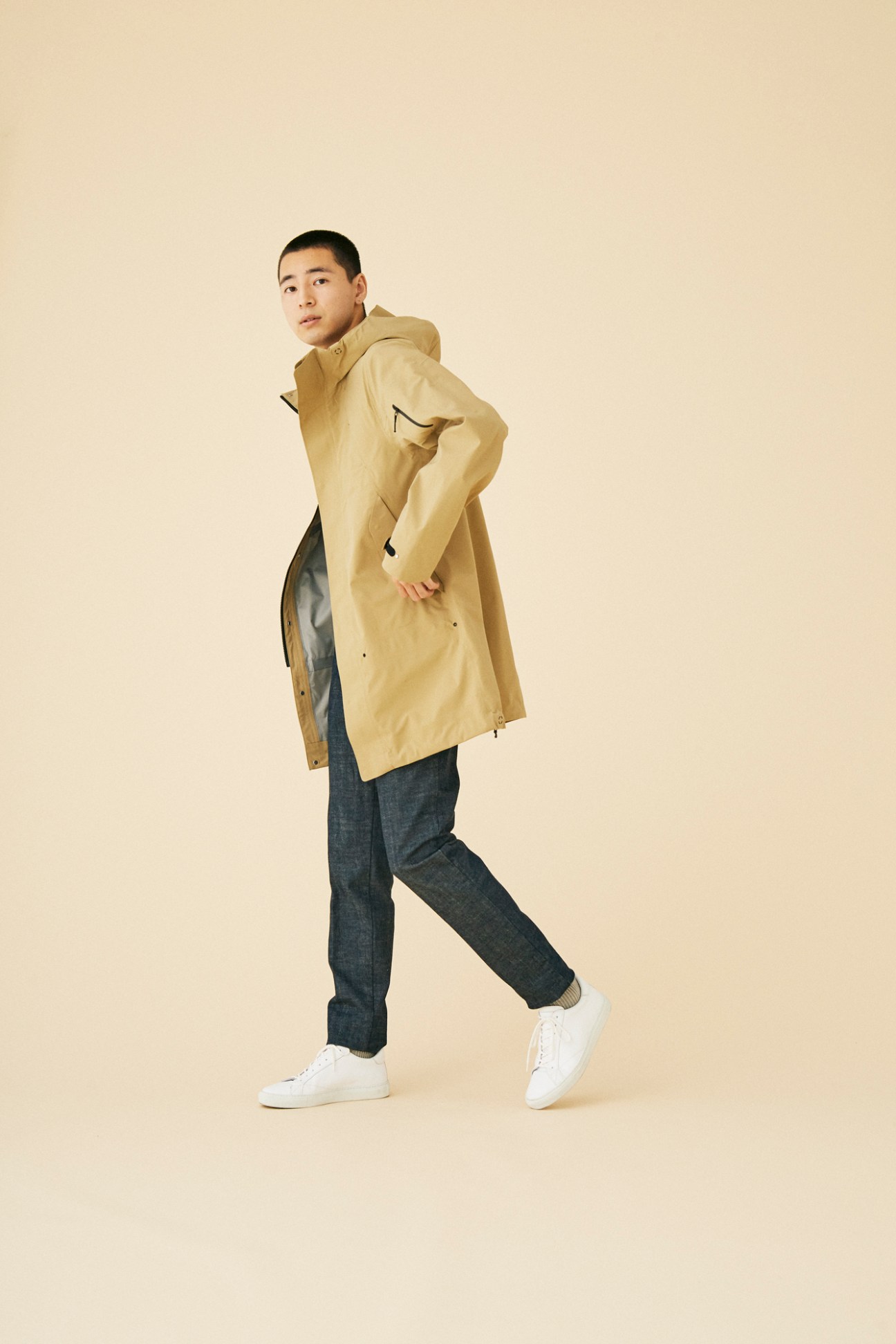 Man wearing technical coat by Goldwin in minimalist studio