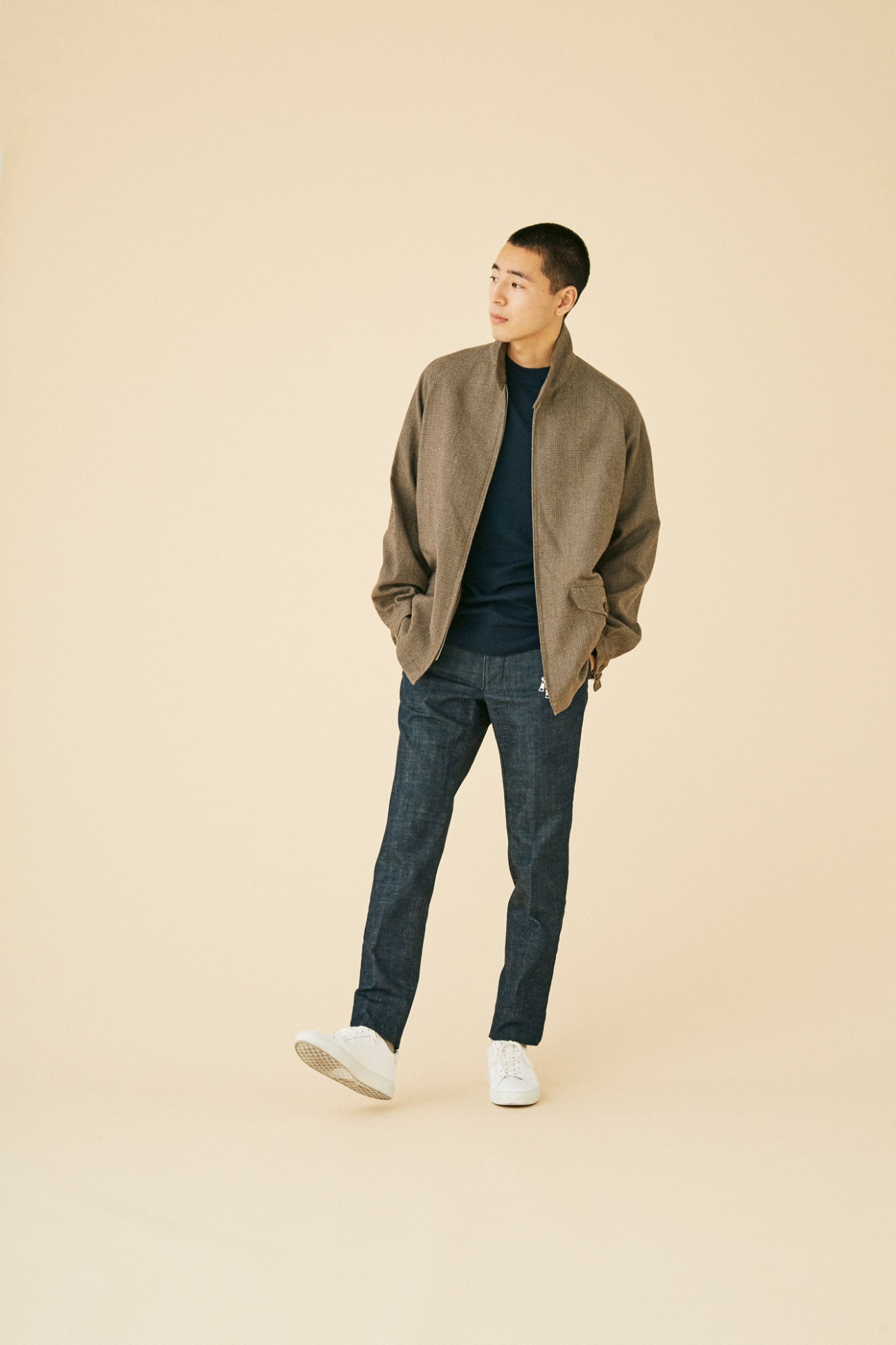 Man wearing brown textured jacket by Kaptain Sunshine with navy shirt and jeans against beige background