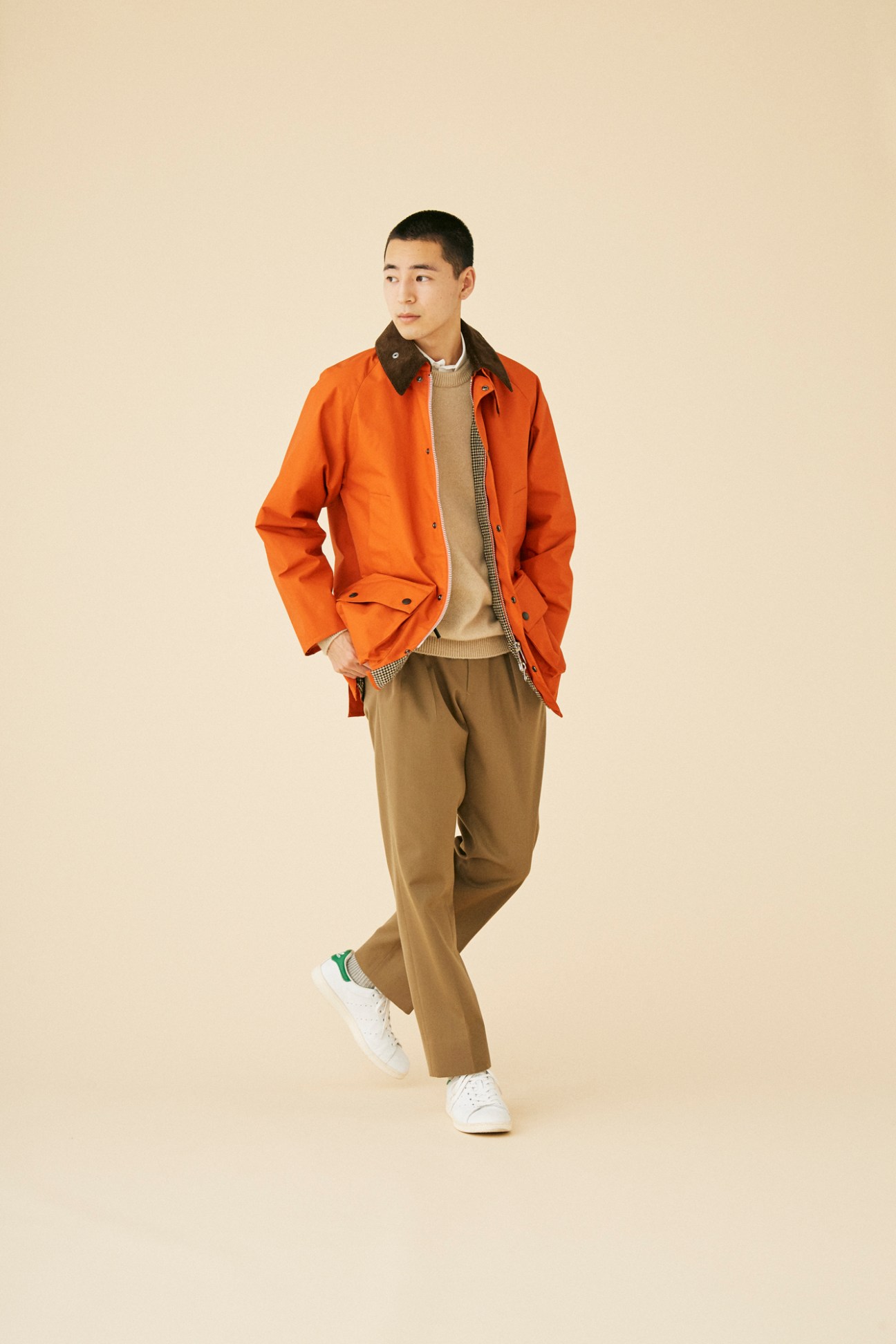 Man wearing orange Barbour jacket with layered winter outfit including beige jumper and trousers