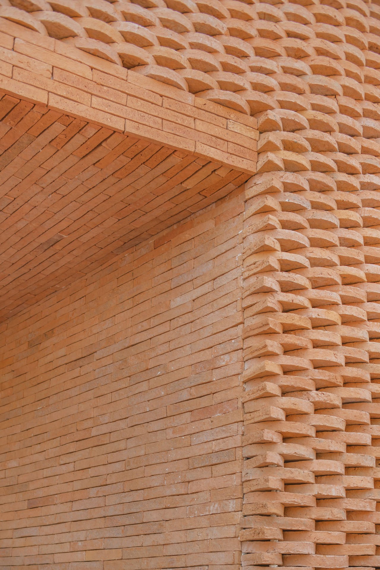 Detail of Central Ayutthaya's latticed orange brick facade showing woven pattern and architectural depth.