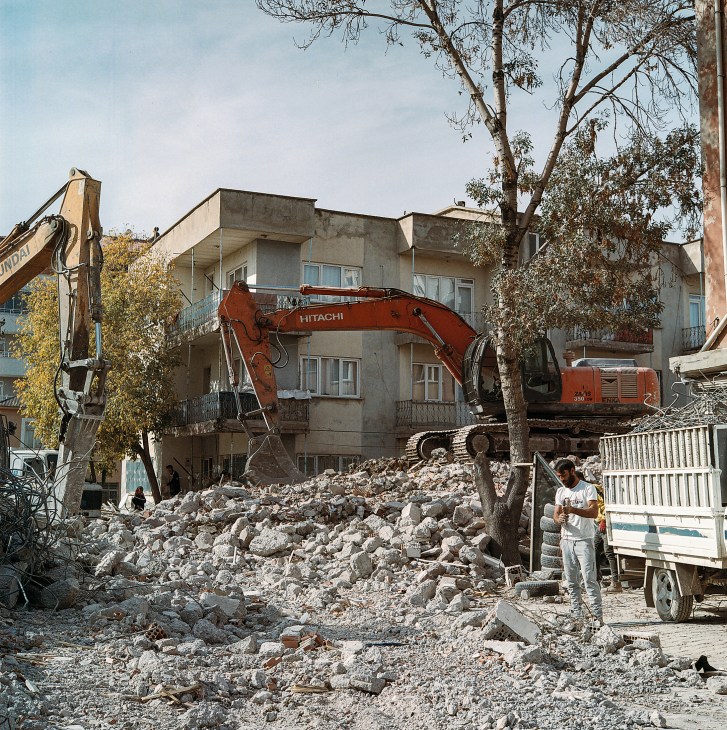 Heavy machinery demolishes a damaged concrete apartment building in Turkey after earthquake destruction.