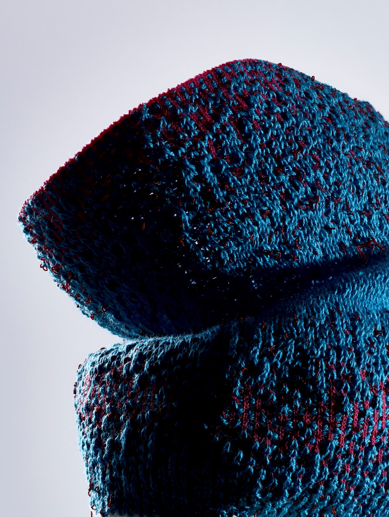 Close-up of blue and burgundy knitted textile material with dimensional sculptural form by Tiffany Loy