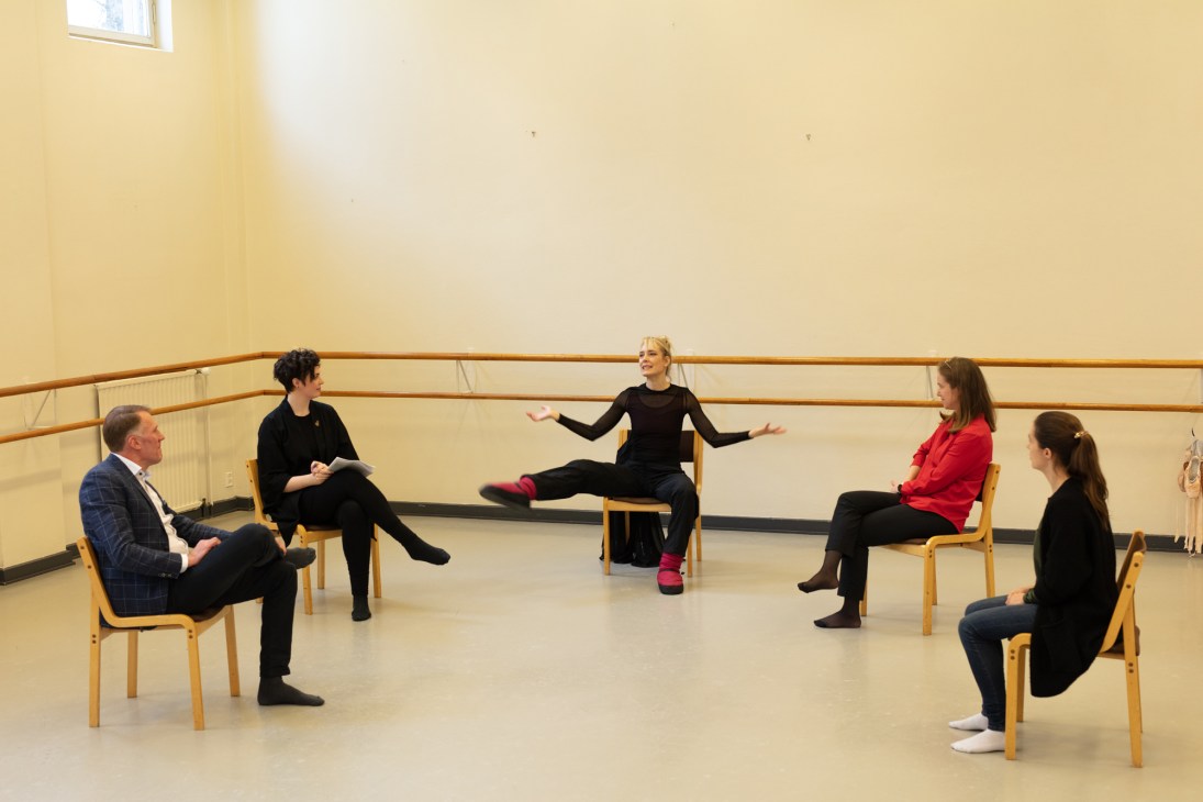 Five people sit in a circle on wooden chairs in a studio space with a ballet barre, appearing to participate in a Co-founders workshop.