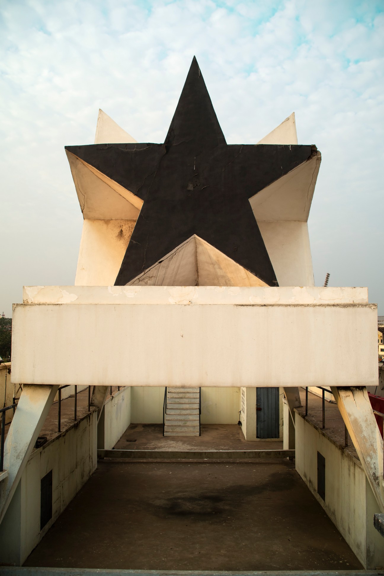 Large black star monument mounted on concrete pillars with stairs leading up beneath it