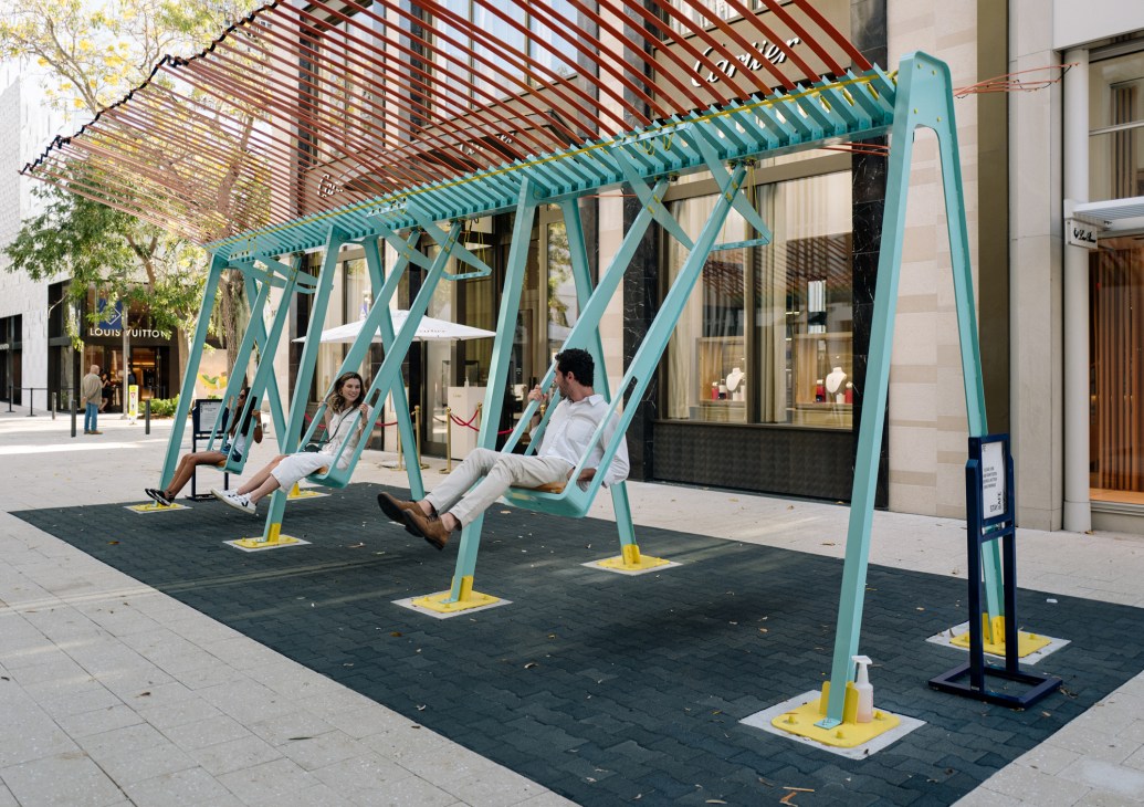 Two people on a turquoise swing installation in Miami's Design District by Chilean studio GT2P