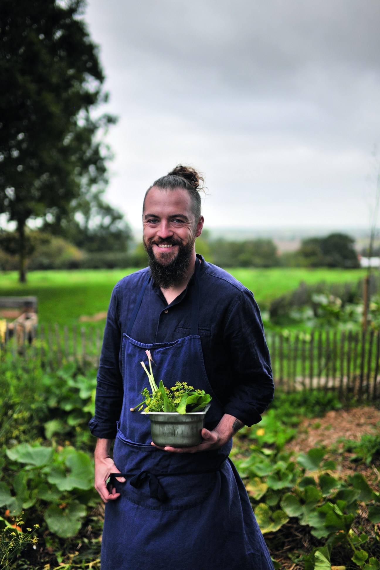 Chef Florent Ladeyn holding a bowl of fresh vegetables in his garden