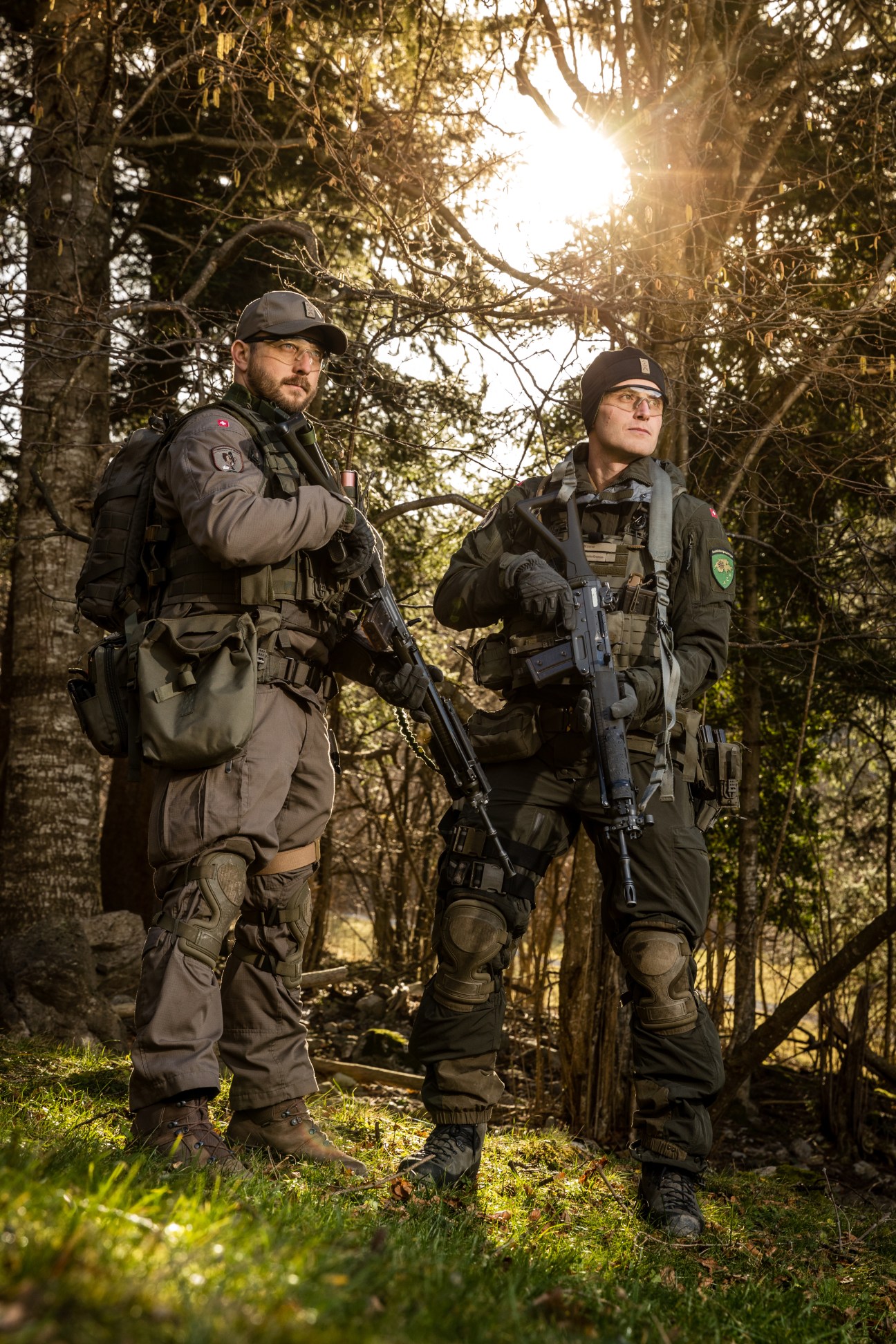 Two Swiss soldiers in camouflage uniforms holding rifles in a wooded area