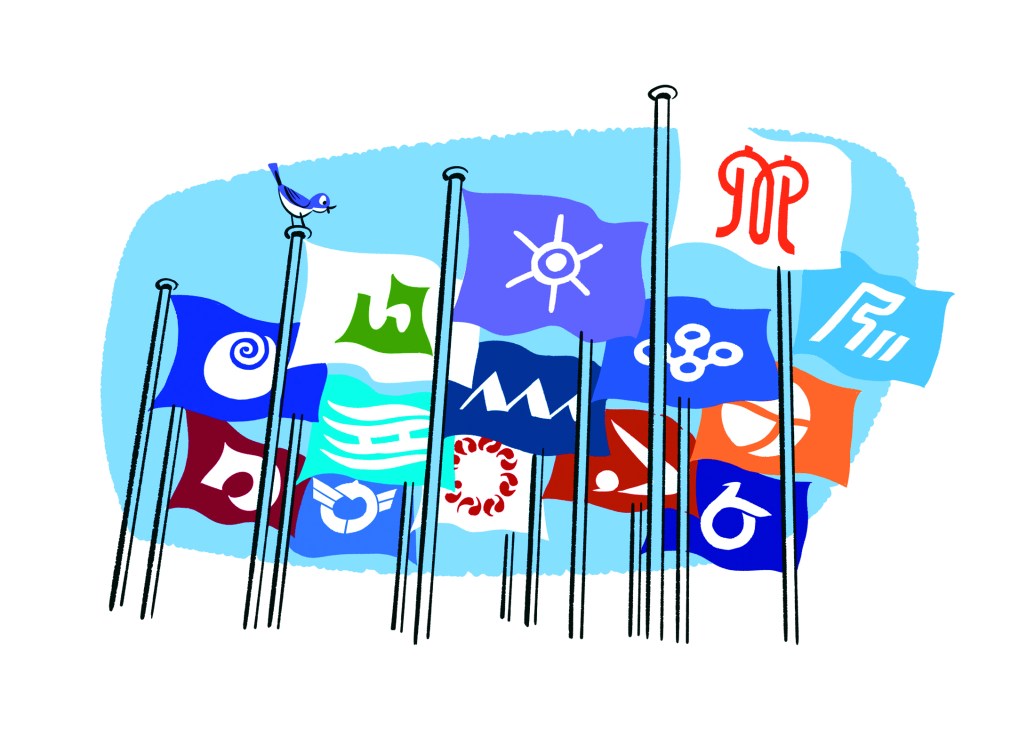 Various colorful flags with different symbols and logos displayed on flagpoles against a blue sky background