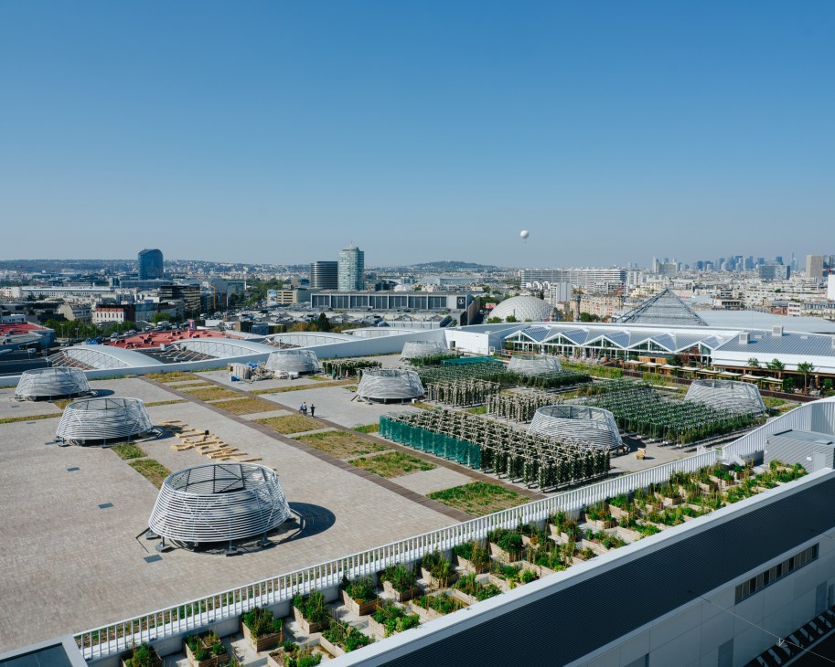 Aerial view of Nature Urbaine rooftop farm with dome structures, growing areas and Paris skyline in background