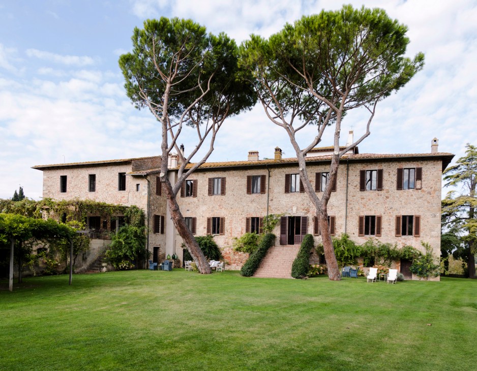 Stone villa exterior with manicured lawn and distinctive umbrella pine trees at La Pescaia Resort in Tuscany