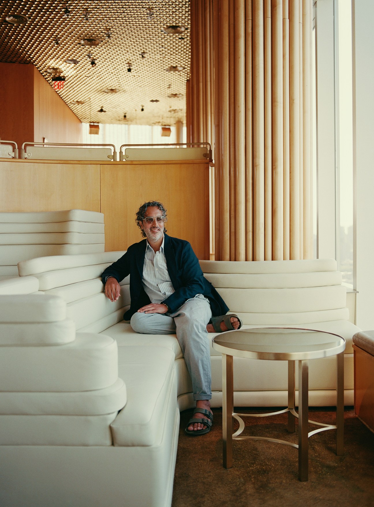Amar Lalvani sitting on an Italian suede couch in the Boom Boom Room overlooking New York City skyline