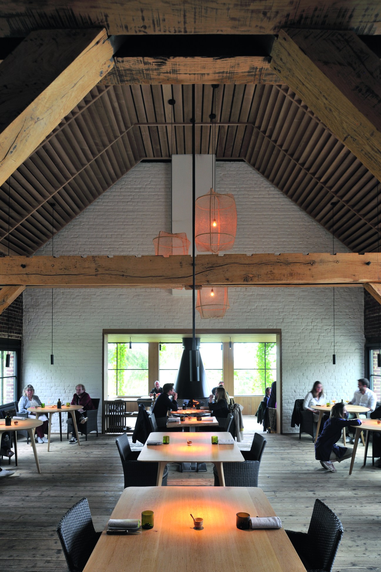 Restaurant dining room with exposed wooden beams, white brick walls, and pendant lighting
