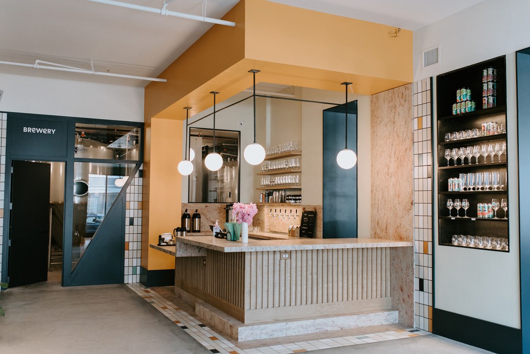 Interior of Talea brewery taproom with wooden bar counter, pendant lighting, and tiled walls