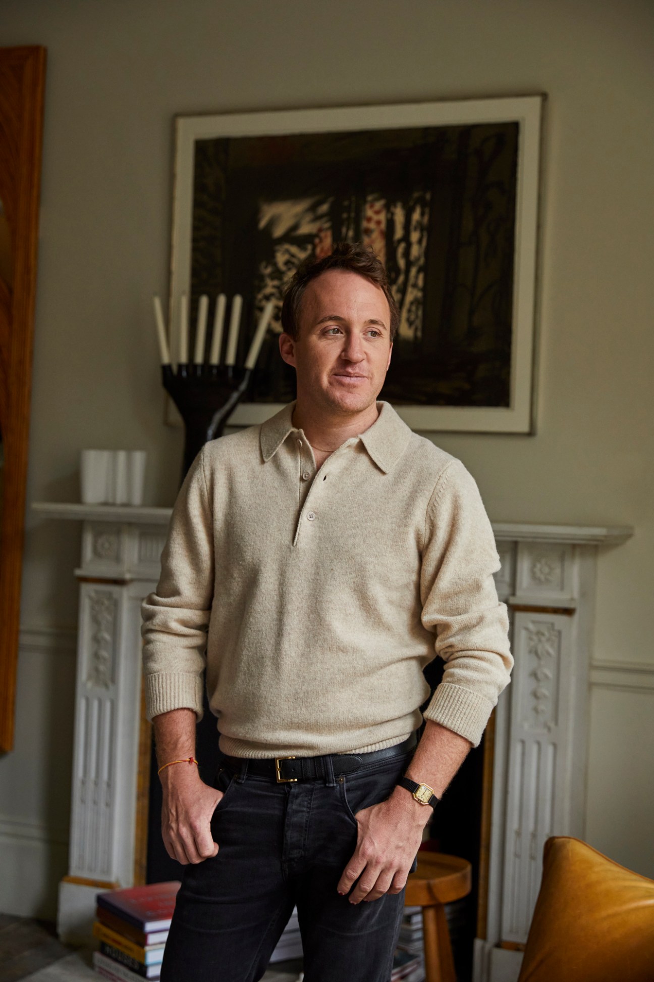 Tobias Vernon standing in elegant interior with fireplace and framed artwork