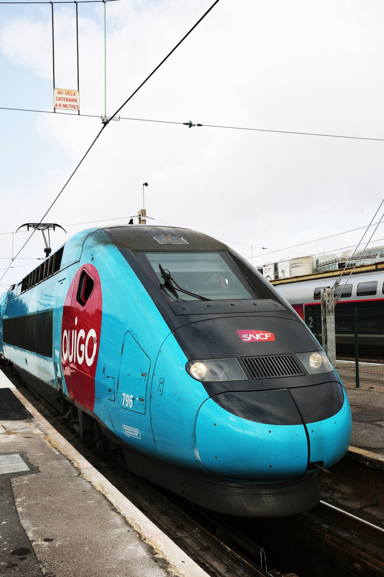 Pink and blue Ouigo high-speed train at platform heading to Marseille