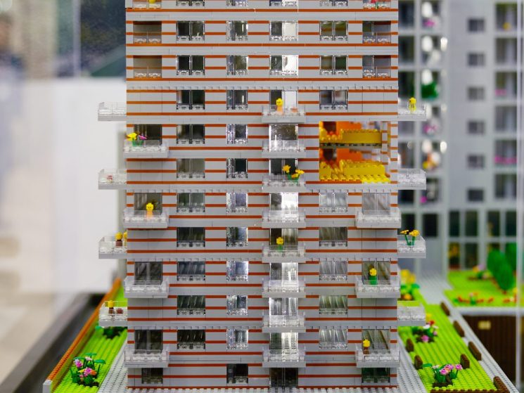 LEGO architectural model of residential apartment building with orange and white facade displayed at property conference