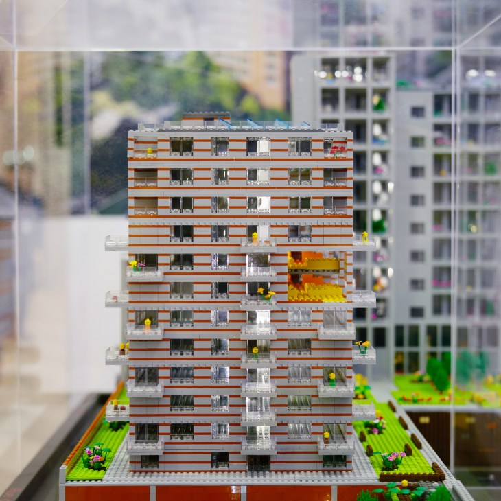 LEGO architectural model of residential apartment building with orange and white facade displayed at property conference