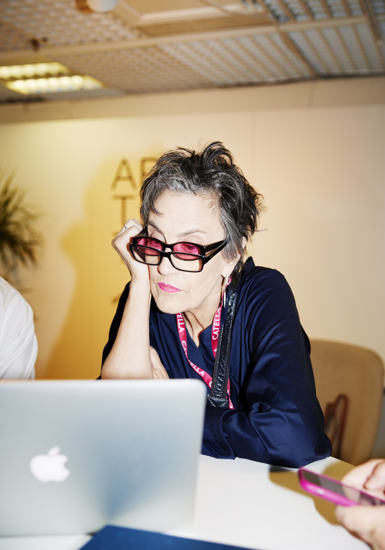 Woman with glasses working at laptop computer looking tired or stressed at conference
