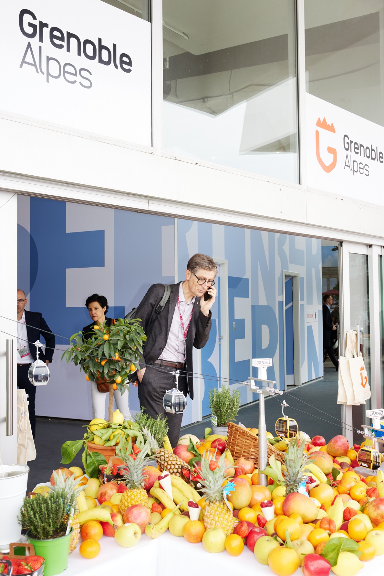 Man in suit on phone at Mipim conference with large fruit display in foreground