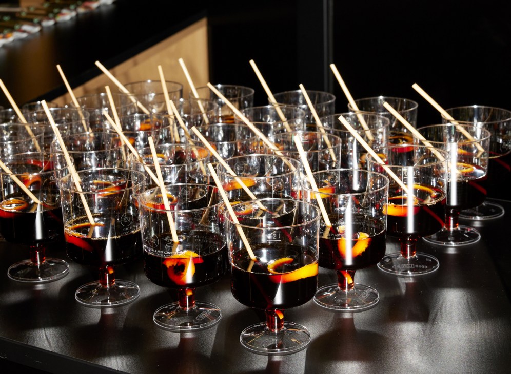 Dark cocktails with orange garnish and wooden stirrers in glass cups at networking event
