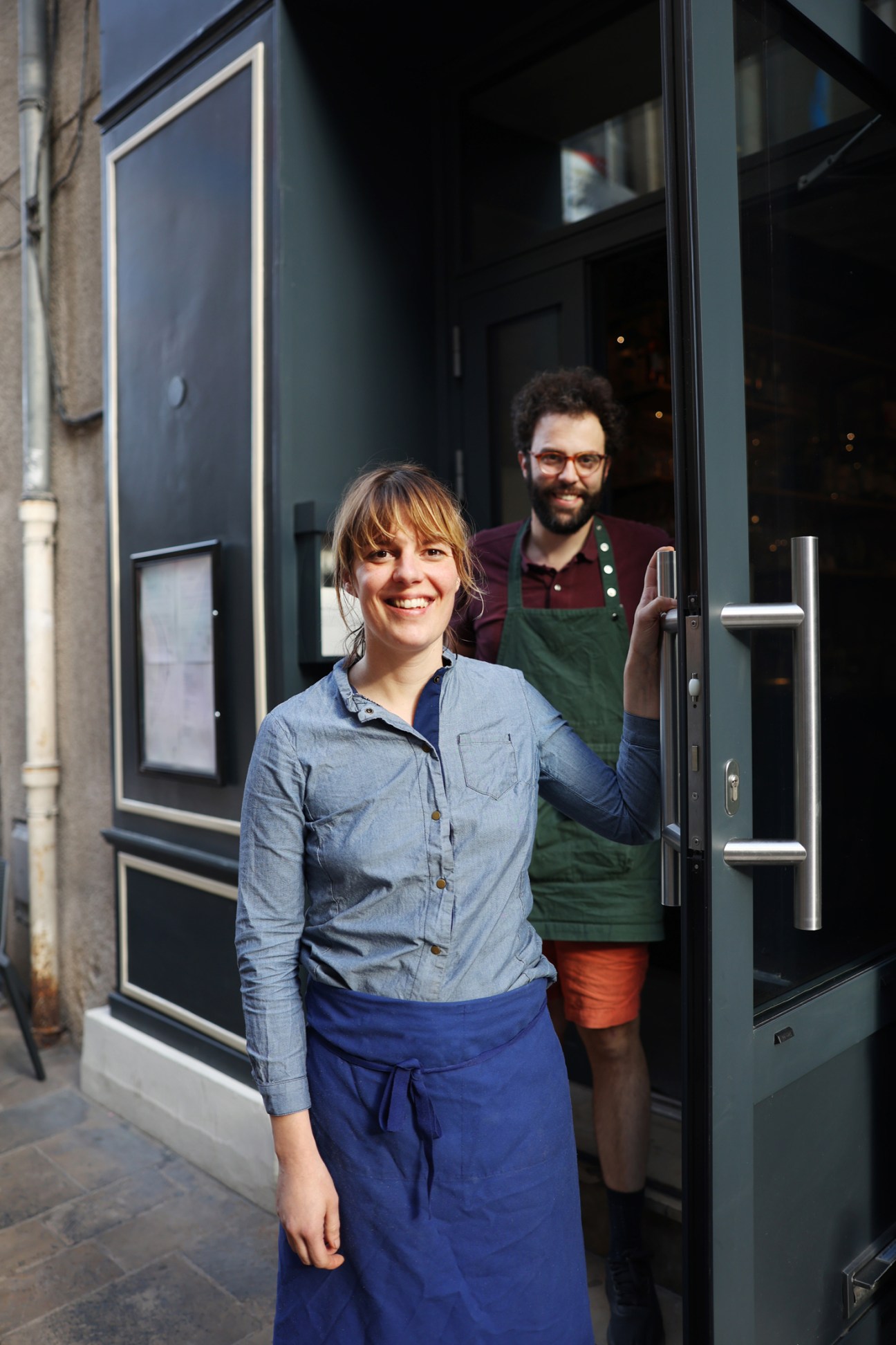 Clara Reydet of restaurant Monique and male colleague standing in doorway of their establishment