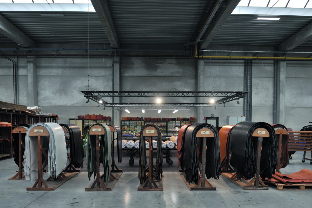 Industrial warehouse interior with concrete walls, exposed ceiling beams and rows of leather materials