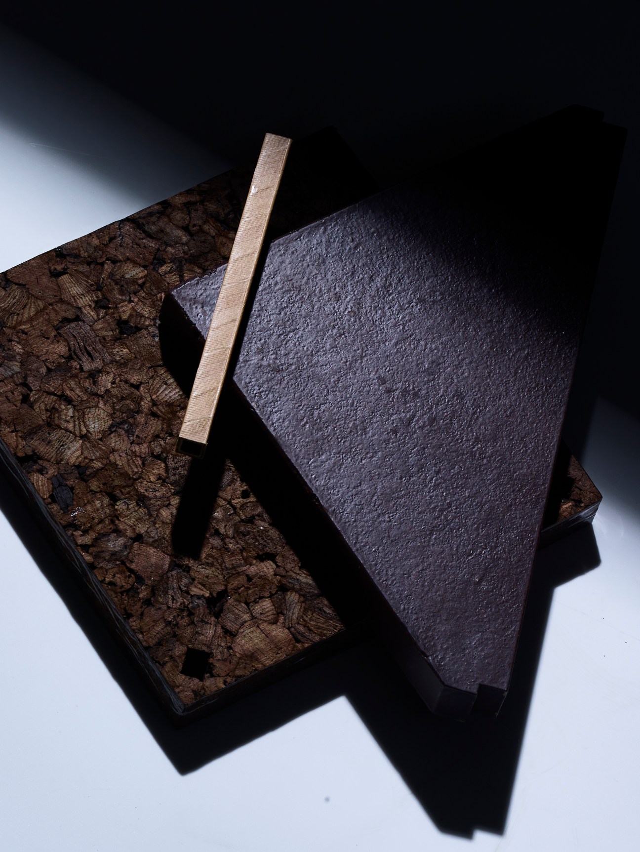 Dark material samples and strips arranged on white surface showing natural fiber biocomposite textures