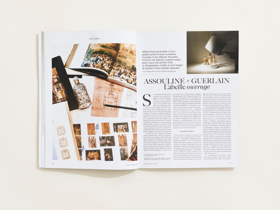 Open magazine spread showing Assouline x Guerlain collaboration article with luxury perfume bottles and books