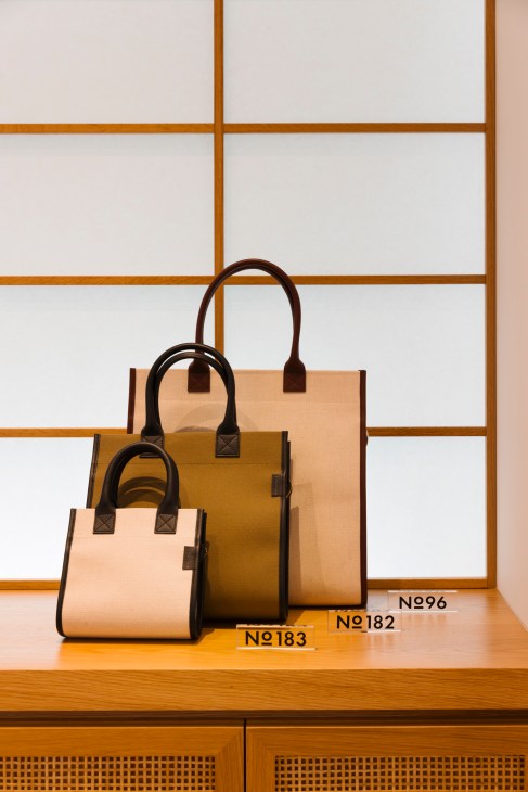 Display of L/Uniform canvas tote bags with leather trim hanging in the Tokyo store