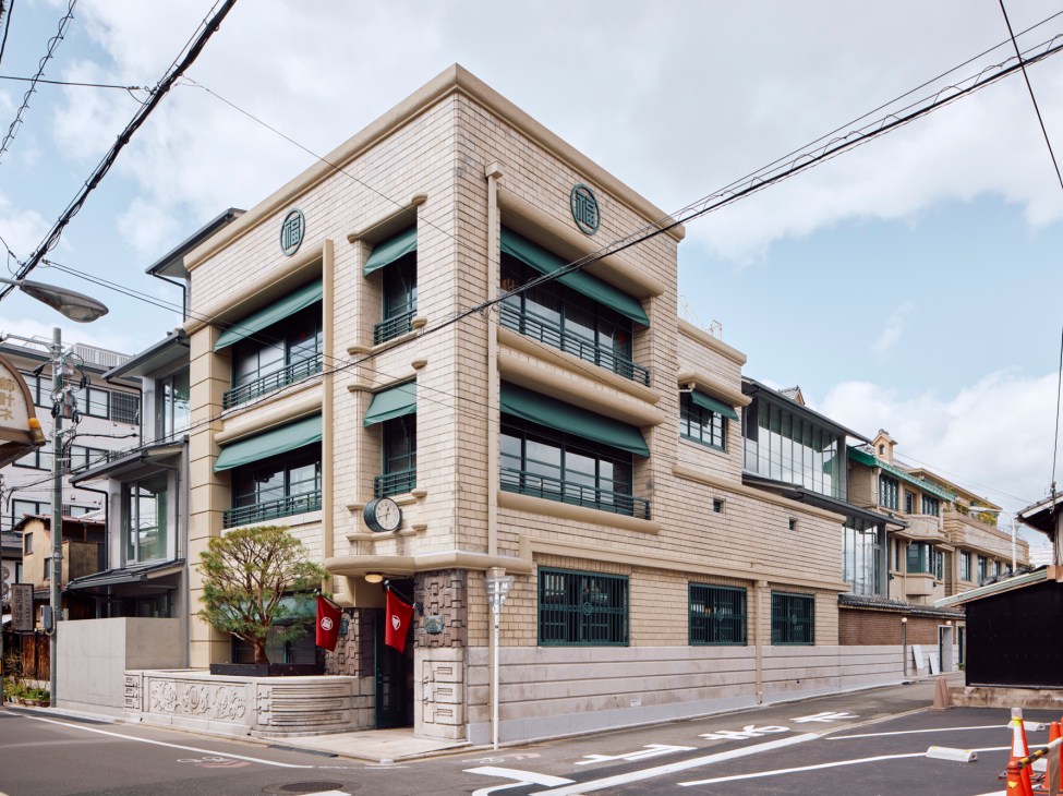 Art deco facade of Marufukuro hotel in Kyoto showing restored 1930s architecture with green awnings