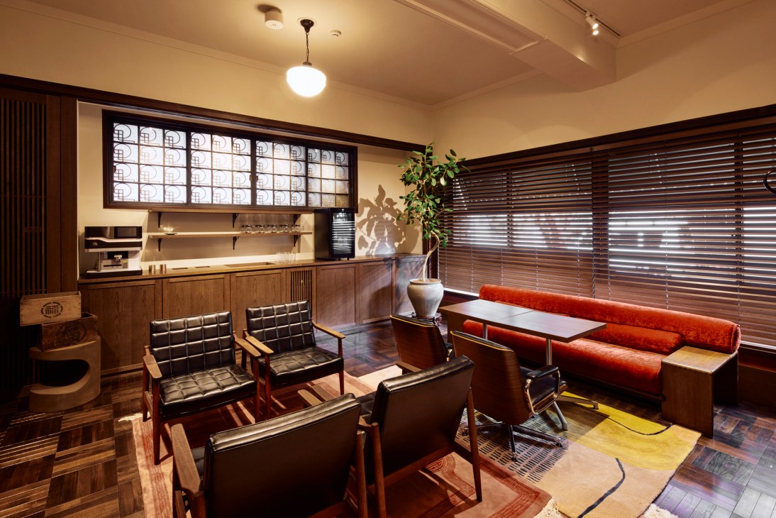 Modern hotel lounge with mid-century furniture, red banquette seating, wooden blinds and warm lighting