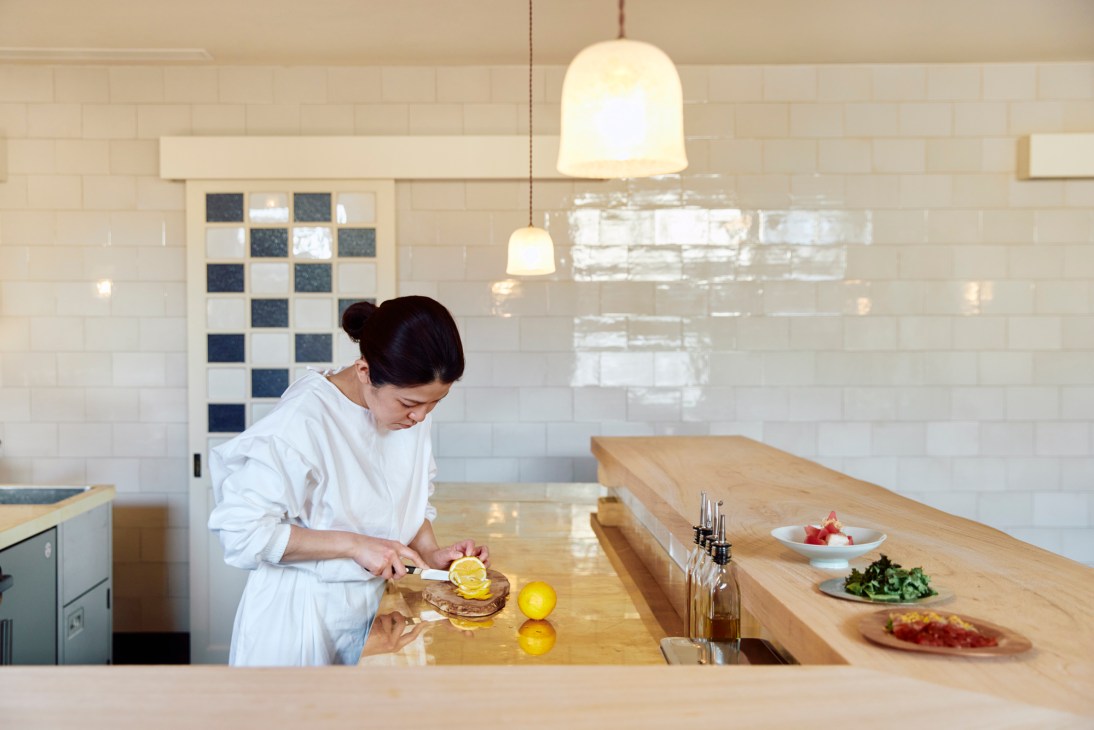 Chef in white uniform preparing food at wooden counter in modern restaurant kitchen