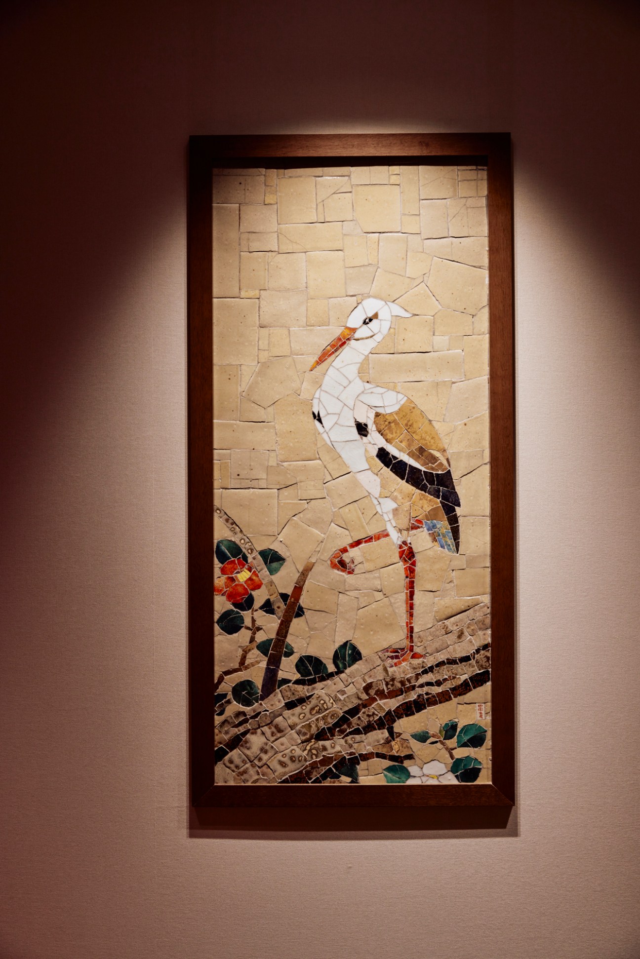 Framed mosaic artwork depicting a white stork with colorful wing details standing among foliage